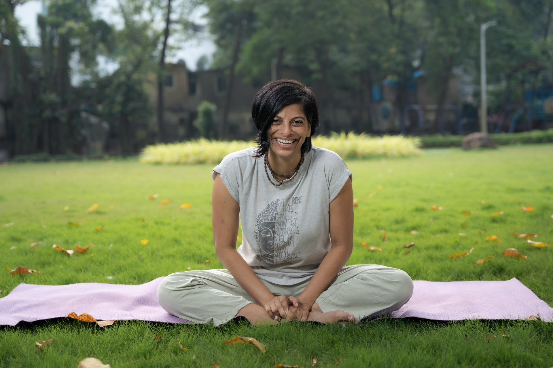 Smitha Shetty seated on a yoga mat in a sunlit garden